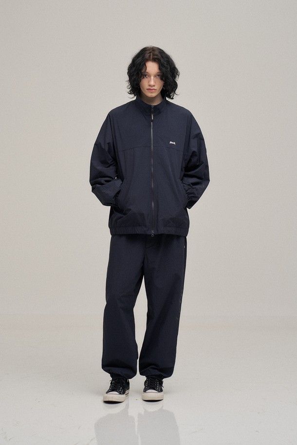 네이비 색상의 Breeze 트레이닝 팬츠입니다. 가볍고 얇은 두께의 나일론 소재로 제작되어 봄철에 적합하며, 루즈핏으로 편안한 착용감을 선사합니다. 허리 밴딩과 밑단 지퍼 트임, 뒷포켓 지퍼 디테일이 돋보이며, YKK 지퍼, 재팬 선그립을 사용하여 활동성을 높였습니다. 르티그레 레터링 투명 프린트와 톤온톤 레터링 자수 디테일로 미니멀하면서도 스포티한 스타일을 연출하며, 일상, 스포츠 활동은 물론 산책룩, 피트니스룩으로 활용하기 좋습니다.
