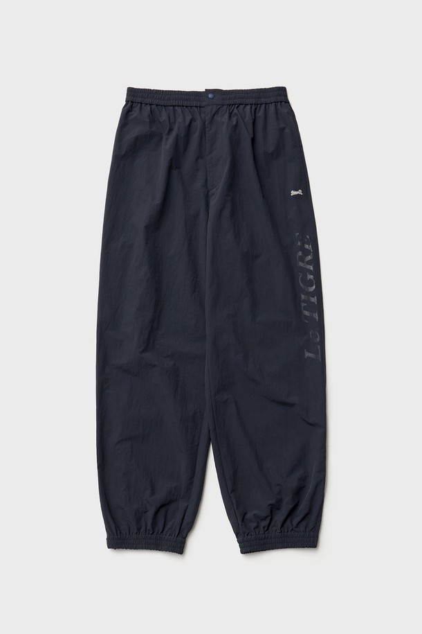 네이비 색상의 Breeze 트레이닝 팬츠입니다. 가볍고 얇은 두께의 나일론 소재로 제작되어 봄철에 적합하며, 루즈핏으로 편안한 착용감을 선사합니다. 허리 밴딩과 밑단 지퍼 트임, 뒷포켓 지퍼 디테일이 돋보이며, YKK 지퍼, 재팬 선그립을 사용하여 활동성을 높였습니다. 르티그레 레터링 투명 프린트와 톤온톤 레터링 자수 디테일로 미니멀하면서도 스포티한 스타일을 연출하며, 일상, 스포츠 활동은 물론 산책룩, 피트니스룩으로 활용하기 좋습니다.
