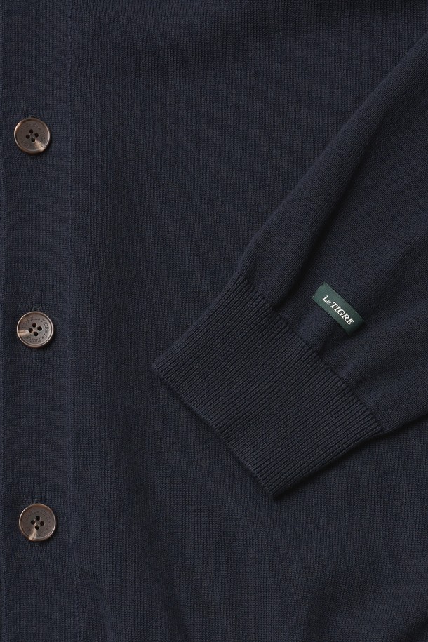 네이비 컬러의 클래식 V넥 가디건입니다. 면 100% 원사를 사용하여 부드러운 촉감을 선사하며, 봄 시즌 데이트룩과 카페룩에 잘 어울립니다. 스탠다드 핏으로 제작되었으며, 소매와 밑단 립조직 마감으로 깔끔함을 더했습니다. 가슴 자수 와펜 디테일과 소맷단 포인트 라벨, 르티그레 레터링 로고 단추가 특징입니다. 베이직하면서도 미니멀한 스타일을 연출하기 좋습니다.
