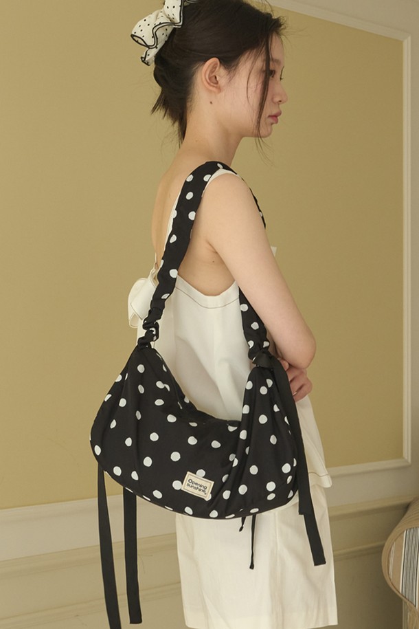 바운티 도트 숄더백_블랙은 부드러운 폴리에스터와 면 소재로 제작되어 편안한 착용감을 선사합니다. 블랙과 화이트 컬러의 도트 무늬가 돋보이며, 반원 모양의 디자인에 리본 장식이 더해져 걸리시하고 로맨틱한 스타일을 연출합니다. 미디엄 사이즈로 넉넉한 수납공간을 제공하며, 내부 작은 포켓과 길이 조절 가능한 스트랩이 실용성을 더합니다. 오픈형 잠금 방식으로 내용물을 쉽게 넣고 꺼낼 수 있으며, 크로스백 또는 토트백으로 활용 가능하여 일상, 여행, 피크닉 등 다양한 용도로 사용하기 좋습니다.
