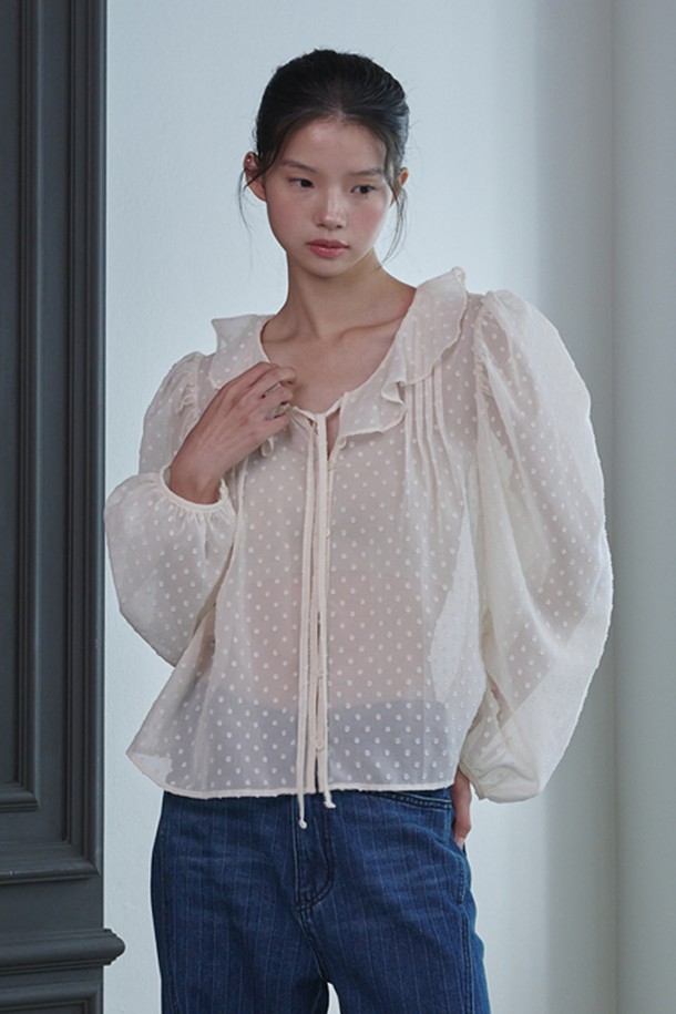 **러플 시스루 도트 블라우스_아이보리**는 페미닌하고 우아한 무드를 연출하는 여성 블라우스입니다. 부드러운 폴리에스테르 소재로 제작되어 봄, 여름, 가을 계절에 착용하기 좋으며, 얇은 두께감으로 시원하게 입을 수 있습니다. 라운드 넥과 긴 소매, 레귤러 핏으로 디자인되었으며, 러플 넥 라인과 스트링 디테일이 여성스러운 포인트를 더합니다. 중앙 버튼 여밈과 시스루 소재, 도트 패턴이 특징이며, 데이트룩, 카페룩, 모임룩 등 다양한 TPO에 클래식, 로맨틱, 미니멀 스타일로 연출하기 좋습니다.
