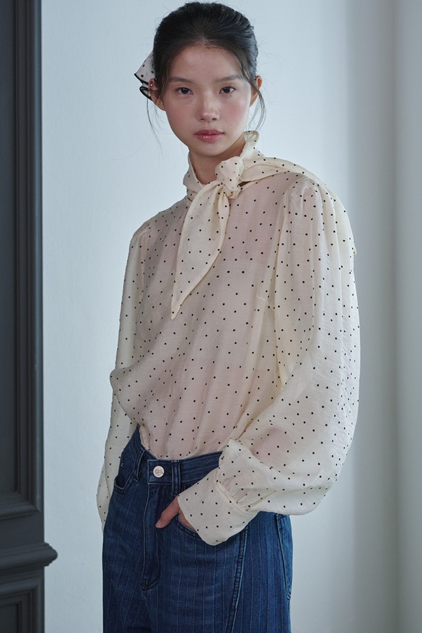 "Dot Scarf Blouse_아이보리"는 여성스러운 무드를 연출하는 블라우스입니다. 부드러운 촉감의 얇은 텍스타일과 나일론 혼방 소재로 제작되어 봄, 여름 시즌에 시원하게 착용하기 좋습니다. 페미닌하고 엘레강스한 스타일을 완성하며, 루즈핏 디자인과 긴 소매, 라운드넥, 도트 패턴이 특징입니다. 특히 퍼프 소매와 숄더 디테일, 뒷목 버튼 고정형 탈부착 스카프가 돋보이며 시스루 소재로 은은한 매력을 더합니다. 데이트룩, 모임룩, 소개팅룩 등 다양한 TPO에 클래식하고 로맨틱한 분위기를 연출할 수 있습니다.
