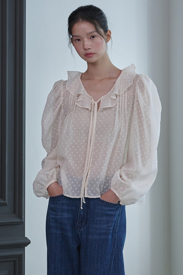 **러플 시스루 도트 블라우스_아이보리**는 페미닌하고 우아한 무드를 연출하는 여성 블라우스입니다. 부드러운 폴리에스테르 소재로 제작되어 봄, 여름, 가을 계절에 착용하기 좋으며, 얇은 두께감으로 시원하게 입을 수 있습니다. 라운드 넥과 긴 소매, 레귤러 핏으로 디자인되었으며, 러플 넥 라인과 스트링 디테일이 여성스러운 포인트를 더합니다. 중앙 버튼 여밈과 시스루 소재, 도트 패턴이 특징이며, 데이트룩, 카페룩, 모임룩 등 다양한 TPO에 클래식, 로맨틱, 미니멀 스타일로 연출하기 좋습니다.
