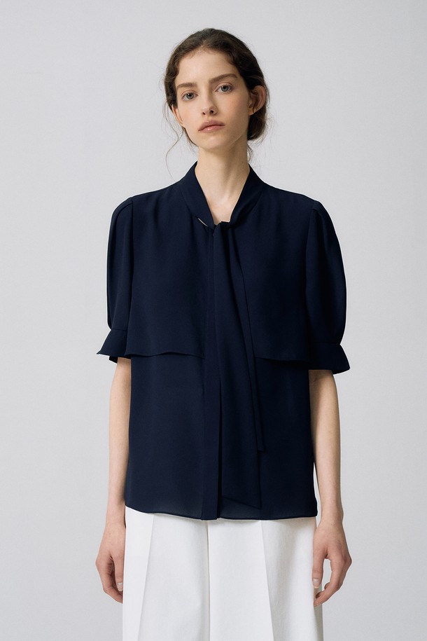 "타이 반소매 블라우스 O5HM23"은 페미닌한 무드의 여성용 블라우스입니다. 다크네이비, 페일핑크, 화이트 3가지 색상으로 출시되었으며, 타이넥 디자인과 반소매 기장이 특징입니다. 얇은 두께감의 폴리에스터 소재로 제작되었으며, 밝은 색상은 비침이 있을 수 있습니다.