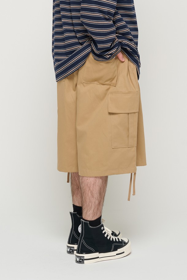 면 소재의 베이지 색상 카고 반바지로, 남녀 모두 편안하게 착용할 수 있는 루즈핏의 벌룬 실루엣 디자인입니다. 밑단 스트링과 사이드 포켓 디테일이 돋보이며, 허리 밴딩으로 일상에서 캐주얼하게 즐겨 입기 좋습니다. 봄, 여름 시즌에 적합하며 부드러운 촉감이 특징입니다.
