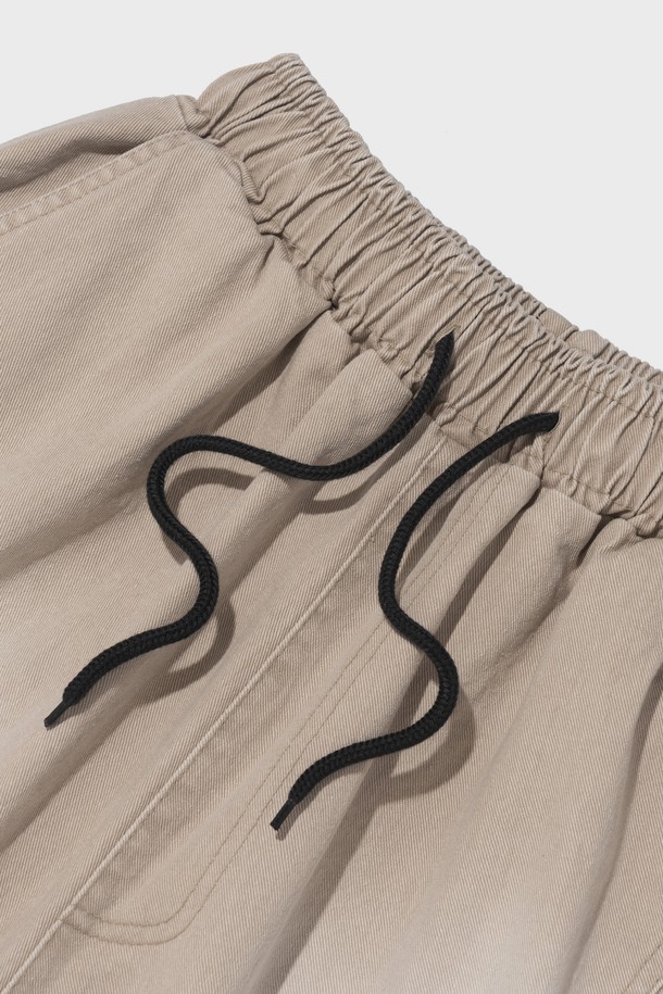 SIDE WAVE CACCION BERMUDA PANTS (BEIGE)는 캐주얼하고 베이직한 스타일의 남녀 공용 버뮤다 팬츠입니다. 면 소재의 루즈핏 와이드 실루엣에 7부 또는 버뮤다 기장으로 제작되었으며, 밴딩 허리로 편안한 착용감을 제공합니다. 베이지, 카키, 그레이 세 가지 색상으로 출시되었으며, 캐션 염색과 사이드 웨이브 디테일이 특징입니다.
