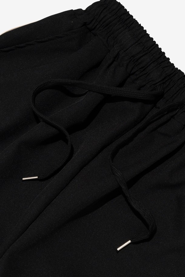 **투턱 테이핑 트레이닝 트랙팬츠 (블랙)**

일상과 스포츠 활동에 모두 적합한 남성용 트레이닝 팬츠입니다. 넉넉한 와이드핏과 긴 기장으로 편안함과 스타일을 동시에 잡았습니다. 폴리에스터 소재로 제작되어 활동성이 높고, 사이드 스트라이프 테이프와 투턱 디테일이 스포티하면서도 스트릿한 무드를 연출합니다. 밴딩 허리 디자인으로 편안한 착용감을 선사하며, 봄, 여름 시즌에 시원하게 입기 좋습니다. 동네 마실룩이나 여행룩으로 활용하기 좋은 캐주얼한 매력의 트레이닝 팬츠입니다.
