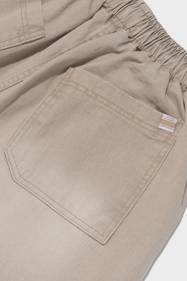 SIDE WAVE CACCION BERMUDA PANTS (BEIGE)는 캐주얼하고 베이직한 스타일의 남녀 공용 버뮤다 팬츠입니다. 면 소재의 루즈핏 와이드 실루엣에 7부 또는 버뮤다 기장으로 제작되었으며, 밴딩 허리로 편안한 착용감을 제공합니다. 베이지, 카키, 그레이 세 가지 색상으로 출시되었으며, 캐션 염색과 사이드 웨이브 디테일이 특징입니다.
