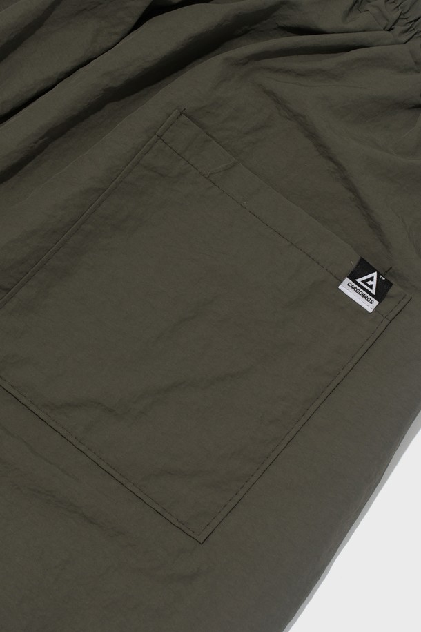 부드러운 촉감의 나일론 소재로 제작된 핀턱 디테일의 버뮤다 팬츠입니다. 루즈핏으로 편안하게 착용 가능하며, 허리 밴딩과 드로우스트링으로 사이즈 조절이 용이합니다. 봄, 여름 시즌 캐주얼 스타일을 연출하기 좋은 5부 기장의 카키색 바지입니다.
