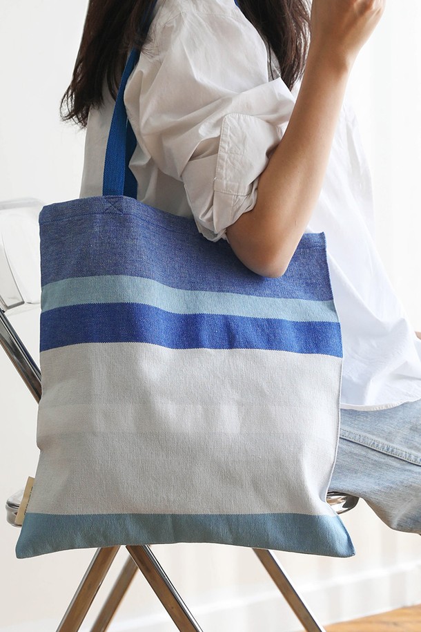 [오리고] 에코백 오가닉코튼 퓨어스카이 2종은 GOTS 인증을 받은 오가닉 코튼으로 제작되어, 무농약 3년 이상 재배된 순수한 면의 질감을 느낄 수 있습니다. 미디엄 사이즈의 사각 에코백으로, 스카이블루, 화이트, 실버그레이 3가지 색상에 스트라이프 패턴이 더해져 캐주얼, 미니멀, 클래식 스타일을 연출합니다. 자연스러운 직조 텍스처와 캔버스 두께감으로 내구성이 뛰어나며, 핸드룸 직조 방식으로 제작되어 A4 사이즈 수납이 가능합니다. 오픈형 디자인에 손잡이가 있어 동네 마실룩, 쇼핑룩, 산책룩 등 일상생활에서 편안하게 사용하기 좋습니다. 유해물질 없이 자연 염색된 오가닉 코튼 에코백으로, 소중한 당신의 하루를 더욱 특별하게 만들어 보세요.
