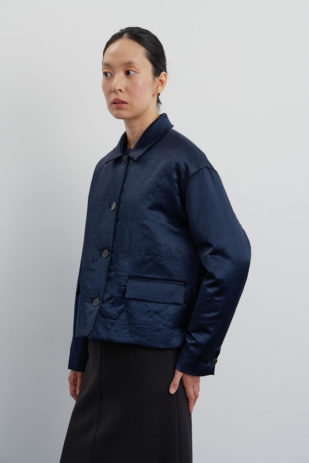 미드나잇 블루 컬러의 여성 패딩 재킷입니다. 실크처럼 부드러운 폴리사틴 소재로 제작되어 은은한 광택감이 돋보이며, 레귤러 핏과 크롭 기장으로 세련된 실루엣을 연출합니다. 안감은 비스코스 소재를 사용하여 편안한 착용감을 선사하며, 소뿔 단추와 입술 모양 단추구멍 디테일이 고급스러움을 더합니다. 가을, 겨울, 봄 시즌 오피스룩, 모임룩, 소개팅룩 등 다양한 TPO에 클래식, 미니멀, 시크 스타일로 활용하기 좋습니다. 얇은 두께감으로 간절기에도 부담 없이 즐겨 입을 수 있습니다.
