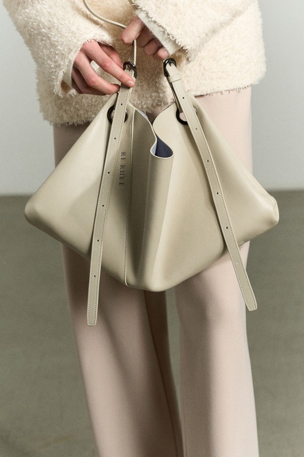 아이보리 베이지 컬러의 ADJUSTABLE STRAP LEATHER BAG(어저스터블 스트랩 레더 백)은 RE RH'EE 컬렉션의 하이엔드 무드를 담은 토트백입니다. 소가죽, 폴리에스터, 폴리우레탄 소재로 제작되었으며, 사선 절개 디테일과 로고 패턴이 특징입니다. 미디엄 사이즈로 토트백, 숄더백, 벨트백, 슬링백 등 3-4가지 스타일로 변형 가능하며 사이즈 조절이 용이합니다. 오피스룩, 모임룩, 소개팅룩 등 다양한 TPO에 맞춰 클래식, 미니멀, 시크한 스타일을 연출할 수 있는 사각 쉐입의 가방입니다.
