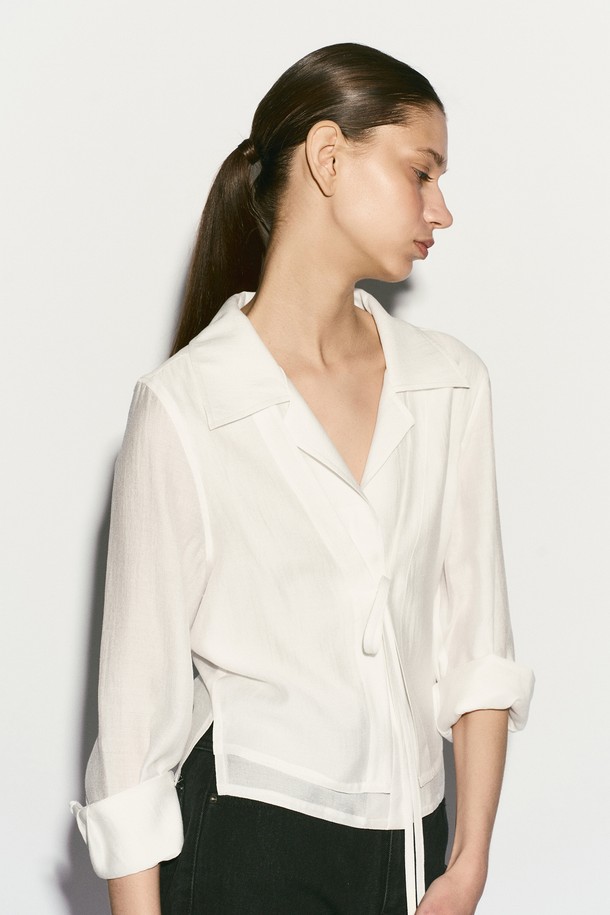 TIE FRONT 레이어드 셔츠는 여성스러운 무드를 연출하는 셔츠/블라우스입니다. 부드러운 촉감의 레이온, 실크, 폴리에스테르 혼방 소재로 제작되어 봄, 여름 시즌에 시원하게 착용하기 좋습니다. 은은한 광택감이 돋보이는 화이트 컬러에 이중 레이어드 디자인과 리본 디테일, 자개 로고 버튼 장식이 더해져 모던하면서도 엘레강스한 스타일을 완성합니다. 레귤러핏과 숄카라, 긴 소매, 크롭 기장으로 디자인되었으며, 데이트룩, 카페룩, 모임룩 등 다양한 TPO에 클래식, 미니멀, 로맨틱 스타일로 코디하기 좋습니다.
