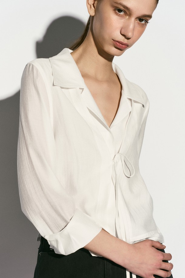 TIE FRONT 레이어드 셔츠는 여성스러운 무드를 연출하는 셔츠/블라우스입니다. 부드러운 촉감의 레이온, 실크, 폴리에스테르 혼방 소재로 제작되어 봄, 여름 시즌에 시원하게 착용하기 좋습니다. 은은한 광택감이 돋보이는 화이트 컬러에 이중 레이어드 디자인과 리본 디테일, 자개 로고 버튼 장식이 더해져 모던하면서도 엘레강스한 스타일을 완성합니다. 레귤러핏과 숄카라, 긴 소매, 크롭 기장으로 디자인되었으며, 데이트룩, 카페룩, 모임룩 등 다양한 TPO에 클래식, 미니멀, 로맨틱 스타일로 코디하기 좋습니다.
