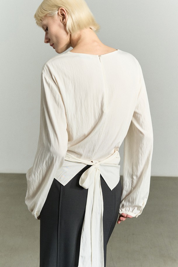 "WAIST WRAP 블라우스 펄"은 여성스러운 분위기를 연출하는 블라우스입니다. 부드러운 레이온과 나일론 혼방 소재로 제작되어 은은한 광택감과 편안한 착용감을 선사합니다. 슬림핏 디자인에 허리 라인을 강조하는 크로스 랩 스타일과 뒷면 매듭 디테일이 특징이며, 셔링 소매로 로맨틱한 무드를 더했습니다. 라운드넥과 긴 소매, 얇은 두께감으로 봄, 여름 데일리룩과 일상룩에 적합하며, 데이트룩, 카페룩, 모임룩 등 다양한 TPO에 활용할 수 있습니다.
