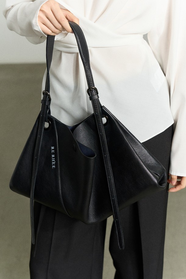 **ADJUSTABLE STRAP LEATHER BAG BLACK (어저스터블 스트랩 레더 백 블랙)**은 미니멀하고 모던한 감각을 더한 여성용 토트백입니다. 소가죽, 폴리에스터, 폴리우레탄 소재로 제작되었으며, 블랙 컬러와 로고 패턴으로 시크한 매력을 선사합니다. 3-4가지 스타일 변형이 가능하여 토트백, 숄더백, 벨트백, 슬링백으로 활용할 수 있으며, 드레이핑 디자인과 하이엔드 무드를 연출합니다. 길이 조절 가능한 스트랩과 RE RH'EE 로고 디테일, 사선 절개 디테일이 특징이며, 출근룩과 오피스룩에 잘 어울립니다. 미디엄 사이즈로 일상에서 실용적으로 사용할 수 있습니다.
