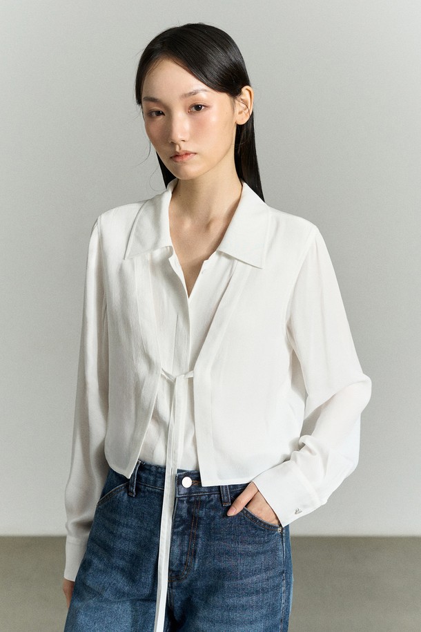 세련된 무드의 FRONT-TIE 레이어드 셔츠 블라우스 화이트입니다. 부드러운 레이온 소재로 제작되어 편안한 착용감을 선사하며, 앞판 이중 레이어드 구조와 리본 디테일이 여성스러운 포인트를 더합니다. 와이드 카라 디자인과 레귤러핏으로 어떤 스타일에도 잘 어울리며, 가을, 겨울 시즌 데이트룩, 카페룩, 모임룩과 같은 TPO에 맞춰 클래식, 미니멀, 로맨틱 스타일을 연출할 수 있습니다. 비침 방지 기능과 자개 로고 버튼으로 고급스러운 마감 처리를 하였으며, 긴 소매 기장과 얇은 두께감으로 레이어드하여 다양한 스타일링을 즐기기 좋습니다.
