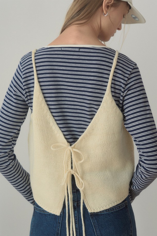 아이보리 컬러의 REAR STRING KNIT VEST(리어 스트링 니트 베스트)입니다. 부드러운 촉감의 니트 소재로 제작되어 봄, 가을 간절기에 활용하기 좋습니다. 크롭 기장의 민소매 디자인으로 캐주얼하고 베이직한 스타일을 연출하며, V넥 라인과 백 리본, 스트링 디테일이 특징입니다. 데이트룩이나 봄 소풍룩에 매치하여 여성스러운 분위기를 더할 수 있습니다. 미니멀, 클래식 스타일을 즐겨 입는 분들께 추천합니다.
