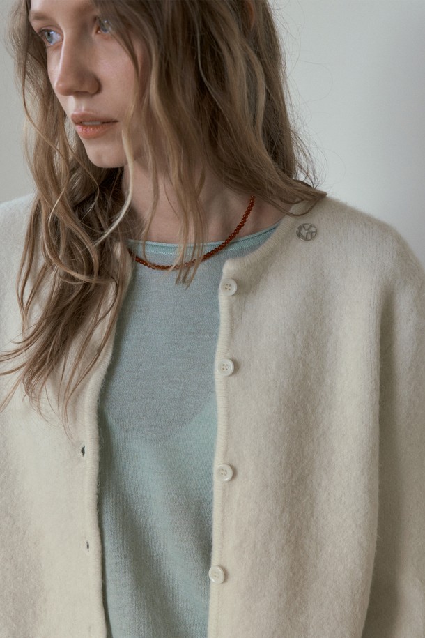 BERY 앙고라 크롭 가디건_아이보리는 여성 의류로, 가을과 겨울에 따뜻하게 입을 수 있는 제품입니다. 부드러운 촉감의 앙고라 소재를 사용하여 포근함을 더했으며, 베이직하고 미니멀한 스타일로 다양한 룩에 활용하기 좋습니다. 라운드넥에 긴소매, 레귤러핏으로 디자인되었으며, 크롭 기장과 버튼 여밈 방식이 특징입니다. 데이트룩, 모임룩 등 TPO에 맞춰 클래식, 미니멀, 캐주얼 스타일을 연출할 수 있습니다.
