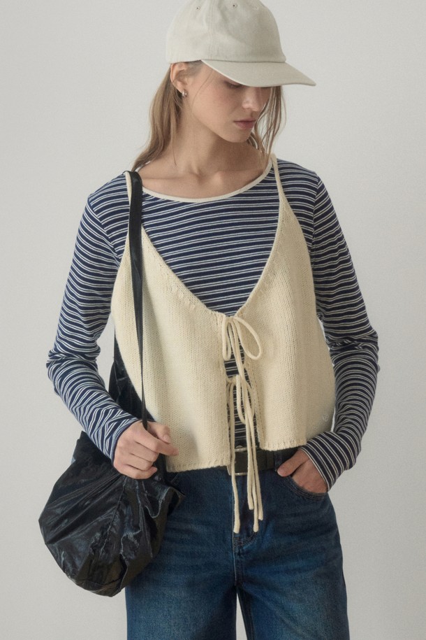 아이보리 컬러의 REAR STRING KNIT VEST(리어 스트링 니트 베스트)입니다. 부드러운 촉감의 니트 소재로 제작되어 봄, 가을 간절기에 활용하기 좋습니다. 크롭 기장의 민소매 디자인으로 캐주얼하고 베이직한 스타일을 연출하며, V넥 라인과 백 리본, 스트링 디테일이 특징입니다. 데이트룩이나 봄 소풍룩에 매치하여 여성스러운 분위기를 더할 수 있습니다. 미니멀, 클래식 스타일을 즐겨 입는 분들께 추천합니다.
