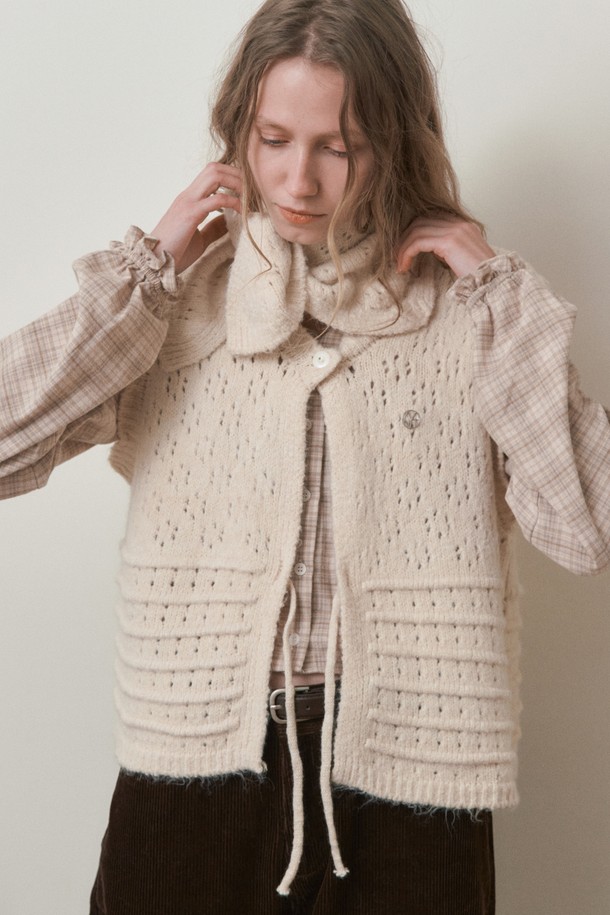 펀칭 스카프 세트 베스트_아이보리는 울, 아크릴, 폴리에스테르 혼방 소재의 여성용 겨울 베스트입니다. 레트로와 빈티지 스타일을 결합한 디자인으로, 펀칭 니트 패턴과 라운드넥, 민소매 디자인이 특징입니다. 부드러운 촉감과 두꺼운 두께로 뛰어난 보온성을 제공하며, 스카프 세트 구성으로 다양한 스타일 연출이 가능합니다. 오버핏으로 편안하게 착용할 수 있으며, 일상복으로 활용하기 좋습니다.
