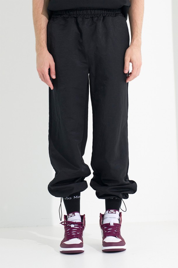 [Plan de Maroon] 윈드브레이커 팬츠는 가볍고 방풍 기능이 있는 블랙 컬러의 유니섹스 윈드브레이커 팬츠입니다. 봄, 가을 시즌에 적합하며, 일상 및 캐주얼 스타일을 위한 레귤러핏 긴바지입니다. 허리 스트링, 밑단 스토퍼, 앞면 포켓, 로고 패치가 특징이며, 스포티하면서도 편안한 착용감을 제공합니다.
