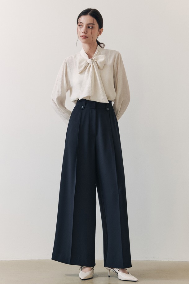 **웨이브 리본 블라우스 / 아이보리**

우아하고 엘레강스한 무드의 여성 블라우스입니다. 아이보리 컬러에 웨이브 텍스처 소재가 돋보이며, 3단 플리츠 타이 디자인과 리본 디테일이 사랑스러운 포인트를 더합니다. 루즈핏으로 편안하면서도 볼륨감 있는 실루엣을 연출하며, 봄, 여름 시즌 데이트룩, 모임룩, 카페룩 등 다양한 TPO에 활용하기 좋습니다. 부드러운 촉감의 레이온과 나일론 혼방 소재로 제작되었으며, 약간의 비침이 있습니다. 클래식, 로맨틱, 미니멀 스타일을 즐겨 입는 분들께 추천합니다.
