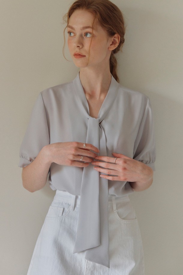 **반팔 타이 블라우스 / 라이트 그레이**

부드러운 촉감과 유연함을 자랑하는 라이트 그레이 컬러의 반팔 타이 블라우스입니다. 가볍고 촤랑거리는 폴리에스테르 소재로 제작되어 여름철에도 시원하게 착용 가능합니다. 우아하고 베이직한 스타일을 연출하며, 벌룬 소매 디자인으로 여성스러움을 더했습니다. 루즈핏과 적당한 두께감으로 편안함을 제공하며, 타이넥 디자인이 세련된 포인트를 선사합니다. 데이트룩, 카페룩 등 다양한 TPO에 클래식, 미니멀, 로맨틱 스타일로 연출해보세요.
