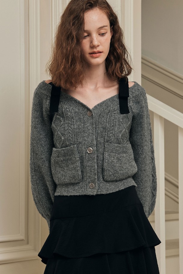 **[2컬러] 프렌치 리본 가디건**은 로맨틱한 무드를 연출하는 여성용 니트 가디건입니다. 부드러운 촉감의 울 블렌드 소재로 제작되었으며, 중간 두께감으로 겨울철 따뜻하게 착용하기 좋습니다. 슬림핏 디자인에 와이드넥으로 여성스러운 실루엣을 강조하며, 트위스트 텍스처 패턴이 특징입니다. 아이보리, 그레이 두 가지 색상으로 출시되었으며, 숄더 리본 스트랩과 볼륨감 있는 소매 라인, 리본 포인트 디테일이 사랑스러운 분위기를 더합니다. 데이트룩, 겨울 데일리룩, 모임룩 등 다양한 TPO에 활용할 수 있습니다.
