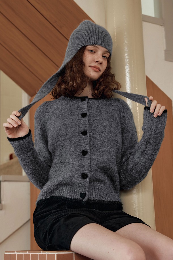**[2컬러] 하트 버튼 라인 가디건**은 여성스러운 무드를 연출하는 가을/겨울용 니트 가디건입니다. 부드러운 촉감의 울 혼방 소재와 보온성 있는 헤어사 소재를 사용하여 따뜻하게 착용할 수 있습니다. 라운드넥 디자인에 넥라인과 밑단 배색, 하트 모양 버튼과 니트 플리팅 디테일이 더해져 러블리하면서도 베이직한 스타일을 완성합니다. 데이트룩, 모임룩 등 다양한 TPO에 클래식, 걸리시, 미니멀 스타일로 코디하기 좋습니다. 그레이, 브라운 두 가지 컬러로 출시되었습니다.
