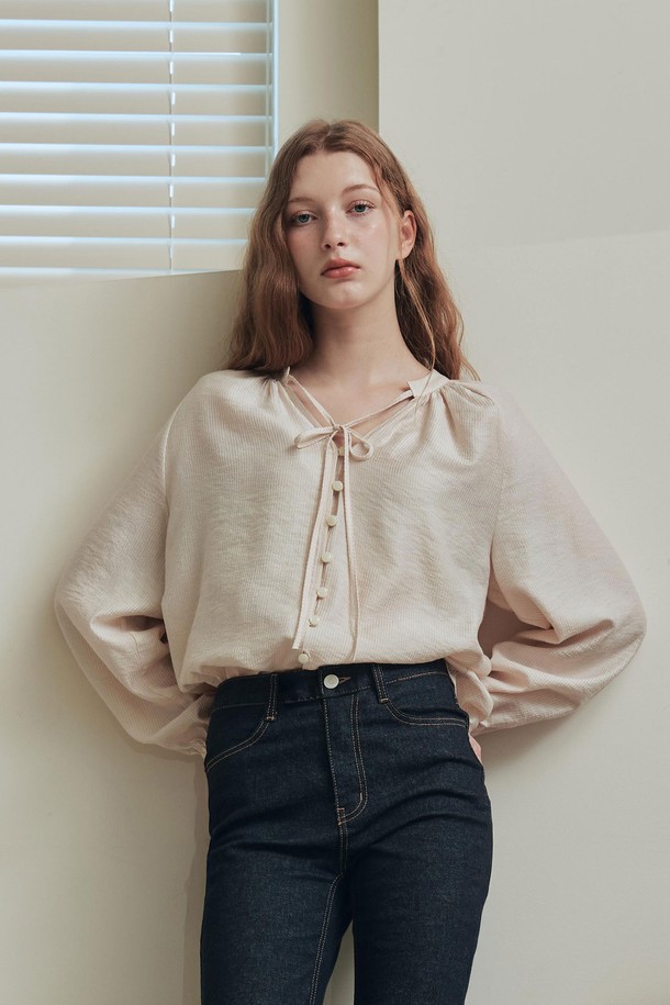 엘리스 블라우스 / 베이지는 여성스러운 무드를 연출하는 블라우스입니다. 부드러운 레이온과 나일론 혼방 소재로 제작되어 봄, 여름 시즌에 시원하게 착용할 수 있습니다. 은은한 광택과 세로 스트라이프 패턴이 우아한 분위기를 더하며, 브이넥 디자인과 루즈핏 실루엣으로 편안함을 선사합니다. 앞중심 버튼, 리본 스트랩, 소매단 셔링과 밴딩 디테일이 돋보이며, 오피스룩, 데이트룩, 모임룩 등 다양한 TPO에 활용 가능합니다. 클래식, 미니멀, 로맨틱 스타일을 즐겨 입는 분들께 추천합니다.
