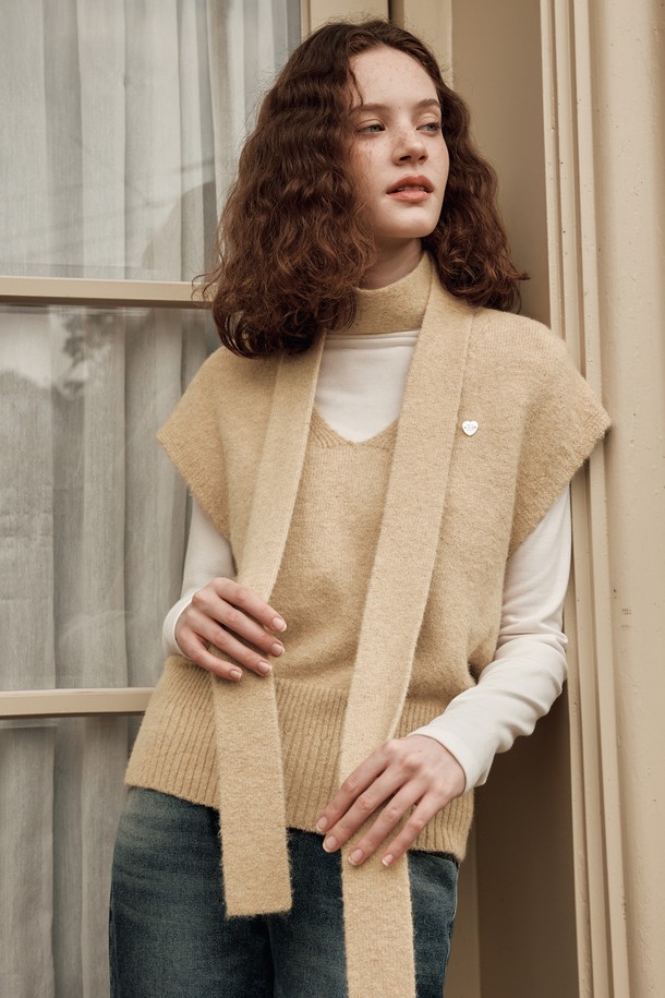 **[2컬러] 하트 펜던트 베스트 머플러 세트**는 부드러운 니트 소재로 제작되어 가을, 겨울철 따뜻함을 선사하는 여성용 베스트입니다. 베이직하고 캐주얼한 스타일로, 레귤러 핏과 브이넥 디자인이 특징이며, 두꺼운 두께감으로 포근하게 착용할 수 있습니다. 하트 패턴과 펜던트 장식, 머플러 세트 구성으로 디자인 포인트를 더했습니다. 블랙, 베이지 두 가지 색상으로 출시되어 다양한 룩에 활용하기 좋습니다.
