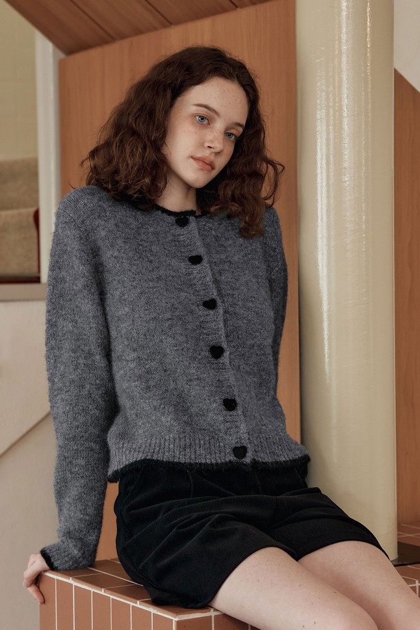 **[2컬러] 하트 버튼 라인 가디건**은 여성스러운 무드를 연출하는 가을/겨울용 니트 가디건입니다. 부드러운 촉감의 울 혼방 소재와 보온성 있는 헤어사 소재를 사용하여 따뜻하게 착용할 수 있습니다. 라운드넥 디자인에 넥라인과 밑단 배색, 하트 모양 버튼과 니트 플리팅 디테일이 더해져 러블리하면서도 베이직한 스타일을 완성합니다. 데이트룩, 모임룩 등 다양한 TPO에 클래식, 걸리시, 미니멀 스타일로 코디하기 좋습니다. 그레이, 브라운 두 가지 컬러로 출시되었습니다.
