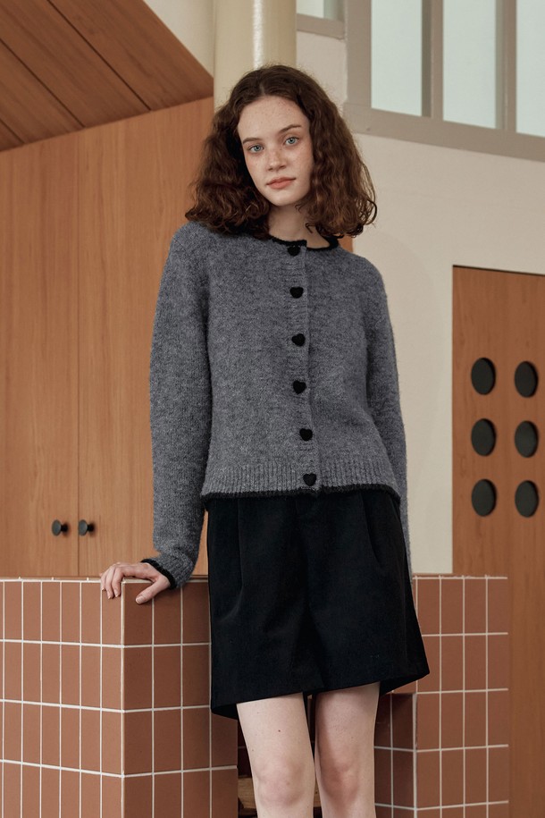 **[2컬러] 하트 버튼 라인 가디건**은 여성스러운 무드를 연출하는 가을/겨울용 니트 가디건입니다. 부드러운 촉감의 울 혼방 소재와 보온성 있는 헤어사 소재를 사용하여 따뜻하게 착용할 수 있습니다. 라운드넥 디자인에 넥라인과 밑단 배색, 하트 모양 버튼과 니트 플리팅 디테일이 더해져 러블리하면서도 베이직한 스타일을 완성합니다. 데이트룩, 모임룩 등 다양한 TPO에 클래식, 걸리시, 미니멀 스타일로 코디하기 좋습니다. 그레이, 브라운 두 가지 컬러로 출시되었습니다.
