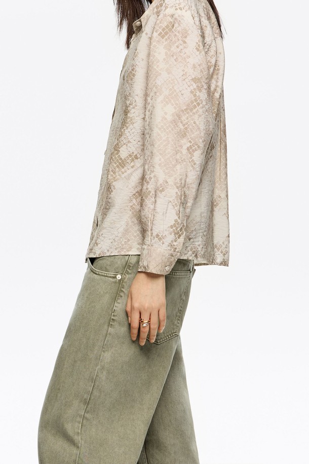 **[25FW] 토프 스네이크 박시 셔츠 B256AWB016BRB**

가을, 겨울 시즌을 위한 여성용 셔츠/블라우스입니다. 토프와 브라운 컬러의 스네이크 패턴 디자인으로, 베이직하면서도 스타일리시한 룩을 연출합니다. 비스코스, 폴리아미드 혼방 소재로 제작되어 부드러운 촉감과 편안한 착용감을 선사합니다. 박시핏과 긴 소매 기장으로 트렌디함을 더했으며, 겨울 데일리룩, 클래식, 미니멀, 캐주얼 스타일을 모두 소화할 수 있습니다. 라운드넥 디자인으로 어떤 스타일에도 잘 어울리는 활용도 높은 아이템입니다.
