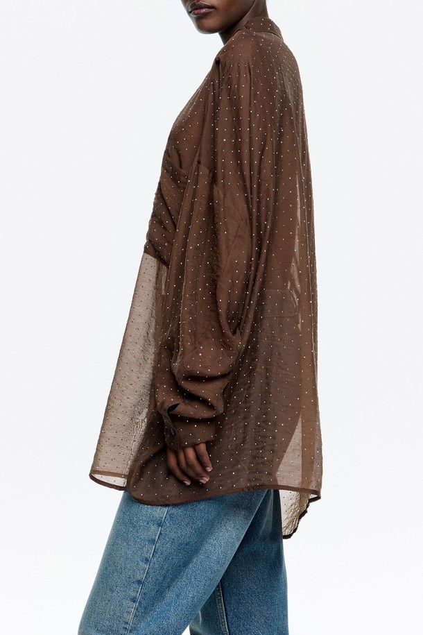 **[25FW] 다크브라운 미니 라인스톤 오버사이즈 셔츠 B256AWB003DWB**는 여성용 셔츠/블라우스로, 다크브라운 컬러에 캐주얼 스타일을 더했습니다. 가을, 겨울 시즌에 어울리는 얇은 두께감의 시스루 셔츠로, 라인스톤 패턴이 특징입니다. 오버핏 디자인과 긴소매 기장으로 편안하면서도 세련된 핏을 연출합니다. 카라 넥 라인으로 단정함을 더하여 일상에서 폭넓게 활용하기 좋습니다.
