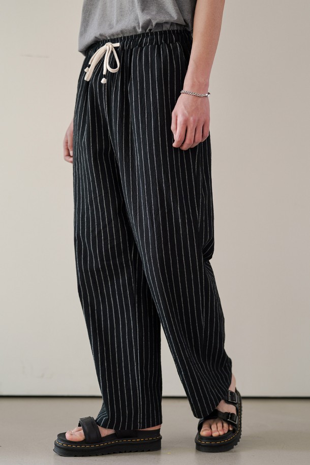 블랙 색상의 썸머 스트라이프 와이드 팬츠 MMLP2628은 남녀 모두 착용 가능한 여름용 긴 바지입니다. 부드러운 촉감의 고밀도 면 스트라이프 원단으로 제작되었으며, 루즈핏 와이드 디자인으로 편안한 착용감을 선사합니다. 허리 스트링, 포켓, 백포켓, 밑단 스티치 등의 디테일과 밴딩 처리로 실용성을 더했으며, 일상 및 리조트룩에 모두 잘 어울립니다.
