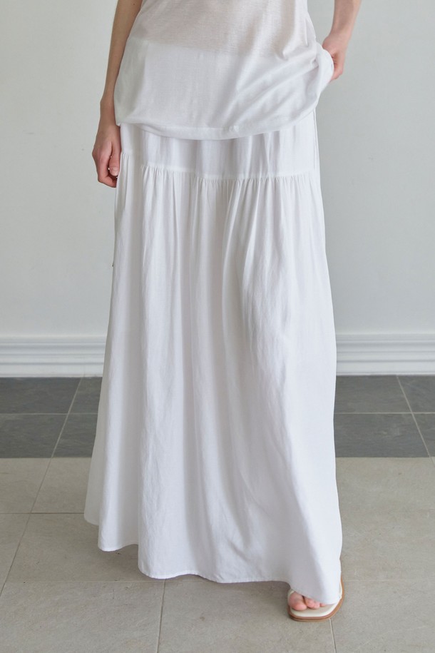 **맥시 스트링 스커트 (2컬러)**

여름 시즌을 위한 여성 맥시 스트링 스커트입니다. 부드러운 레이온, 린넨, 폴리에스터 혼방 소재로 제작되었으며, A라인 핏과 넉넉한 루즈핏으로 편안한 착용감을 선사합니다. 허리 스트링과 밴딩 디테일로 체형에 맞게 조절 가능하며 플레어 디자인이 여성스러운 실루엣을 연출합니다. 화이트, 블랙 두 가지 색상으로 출시되었으며, 안감이 있어 비침 걱정 없이 즐겨 입을 수 있습니다. 미니멀, 리조트, 클래식 스타일을 연출하기 좋으며, 여행, 휴가, 리조트룩에 적합합니다.
