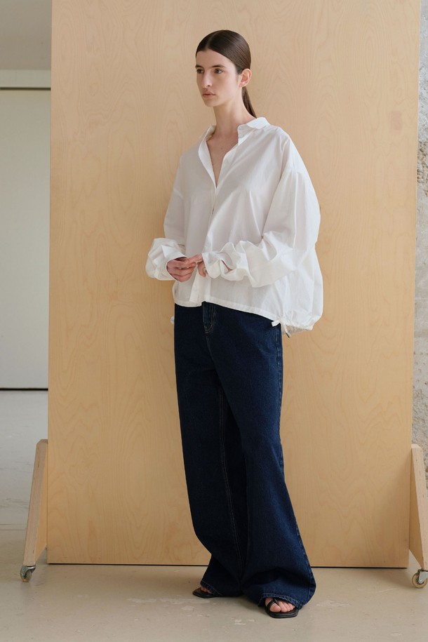 **스트링 볼륨 셔츠**

미니멀하고 베이직한 스타일의 여성용 셔츠/블라우스입니다. 아이보리 컬러의 얇은 면 소재로 제작되었으며, 봄 시즌에 적합합니다. 브이넥 디자인과 루즈핏, 오버핏의 편안한 착용감을 선사하며, 볼륨감 있는 구조적 디자인과 플리츠 디테일이 특징입니다. 뒷면 스트링 디테일로 포인트를 더했고, 60수 고밀도 바이오 원단을 사용하여 부드러운 촉감을 느낄 수 있습니다. 데이트룩, 카페룩, 미니멀, 클래식, 캐주얼 스타일을 연출하기 좋습니다.
