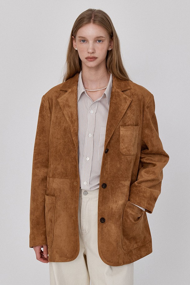 부드러운 스웨이드 소재의 브라운 블레이저 재킷입니다. 미니멀하고 클래식한 디자인으로, 오피스룩, 비즈니스 캐주얼, 모임룩 등 다양한 TPO에 활용하기 좋습니다. 가을 시즌에 적합하며, 얇은 두께감과 오버핏으로 편안한 착용감을 선사합니다. 숄더 패드 디테일과 브랜드 로고가 각인된 버튼, 절개 디테일이 돋보이며, 긴 소매와 싱글 버튼 여밈으로 시크한 스타일을 연출합니다.
