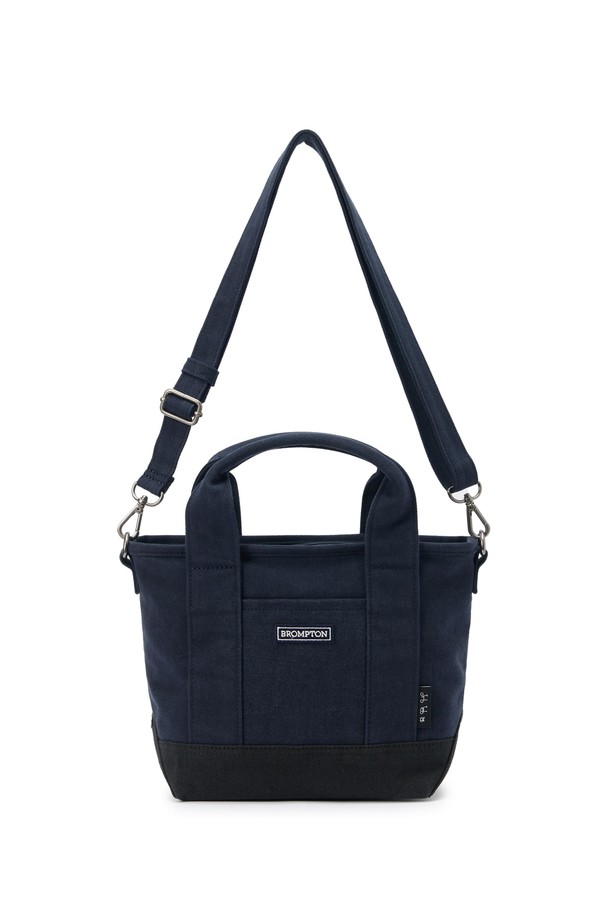 SMALL TOTE BAG (스몰 토트백) - 네이비 컬러의 남성용 토트백입니다. 면 소재로 제작되었으며, 스몰 사이즈의 사각 쉐입에 로고 패턴과 스터드/찡 및 자수 디자인 장식이 돋보입니다. 2WAY 기능과 손잡이로 다양한 연출이 가능하며, 넓은 개구부와 자연스러운 워싱 텍스처가 특징입니다. 오픈형 잠금 방식으로 편리하며, 크로스백으로도 활용 가능하여 동네 마실룩, 쇼핑룩 등 캐주얼, 미니멀, 시티보이 스타일을 연출하기 좋습니다.
