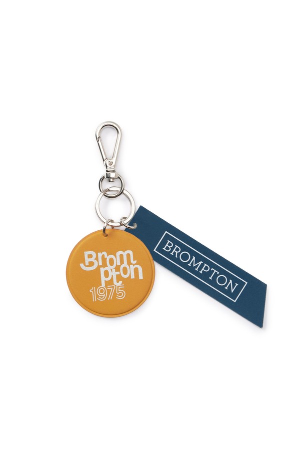 머스타드 색상의 BICYCLE GRAPHIC KEYRING (바이시클 그래픽 키링)입니다. 인조가죽과 폴리우레탄 소재로 제작되었으며, 클래식과 레트로 스타일을 담았습니다. 엠보싱 디자인과 브롬톤 자전거 폴딩 로고 불박 처리가 특징이며, 실버 컬러의 'BROMPTON 1975' 타이포 그래픽이 돋보입니다. 일상, 사이클 용도로 사용 가능하며 야간 라이딩 시 안전을 위한 재귀반사 기능을 제공합니다. 동네 마실룩, 산책룩, 여행룩에 미니멀하게 포인트를 줄 수 있는 아이템입니다.
