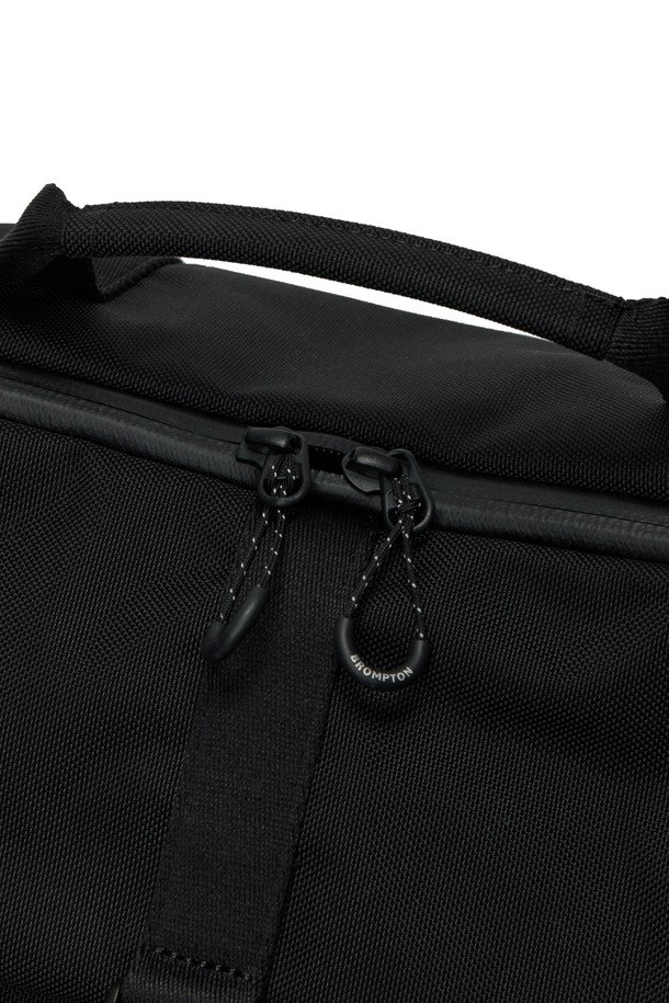 브롬톤 트래블 백 (BROMPTON TRAVEL BAG) - 블랙 (P255ABB151)은 일상과 레저, 자전거 활동에 모두 적합한 가방입니다. 블랙과 그레이 컬러, 미디엄 사이즈로 출시되었으며, 나일론과 폴리에스테르 소재를 사용하여 내구성이 뛰어납니다. 사각 모양에 브롬톤 로고 버클과 오렌지 라벨 포인트가 돋보이며, 벨크로형 잠금 방식으로 편리하게 사용할 수 있습니다. 15.7L의 넉넉한 볼륨으로 헬멧 수납이 가능하며, 크로스백과 토트백으로 활용 가능한 실용적인 디자인입니다.
