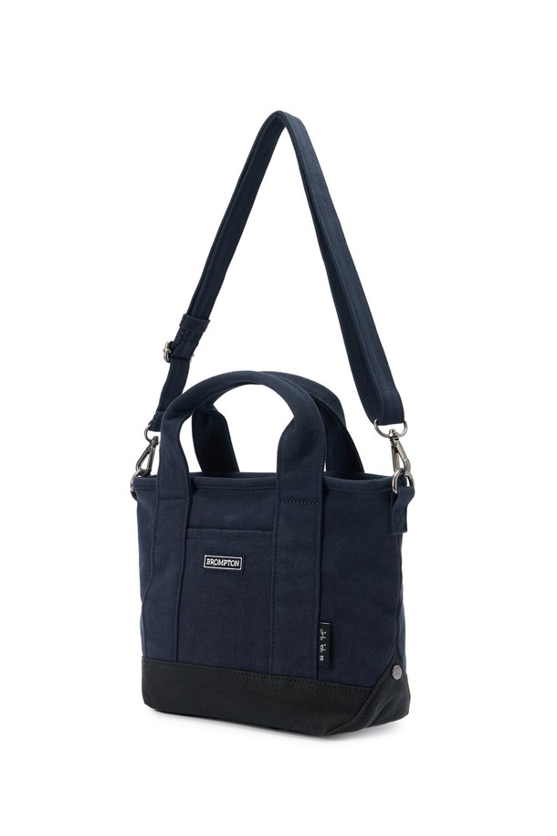 SMALL TOTE BAG (스몰 토트백) - 네이비 컬러의 남성용 토트백입니다. 면 소재로 제작되었으며, 스몰 사이즈의 사각 쉐입에 로고 패턴과 스터드/찡 및 자수 디자인 장식이 돋보입니다. 2WAY 기능과 손잡이로 다양한 연출이 가능하며, 넓은 개구부와 자연스러운 워싱 텍스처가 특징입니다. 오픈형 잠금 방식으로 편리하며, 크로스백으로도 활용 가능하여 동네 마실룩, 쇼핑룩 등 캐주얼, 미니멀, 시티보이 스타일을 연출하기 좋습니다.
