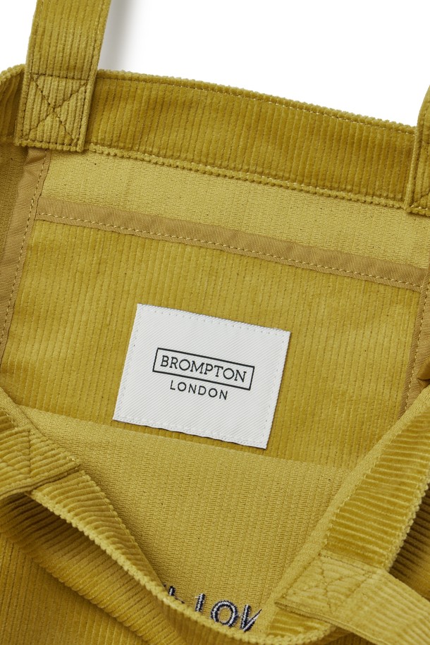 **코듀로이 에코 백 - 머스타드 (P255ATO413)**

부드러운 촉감의 코듀로이, 면, 폴리에스테르 혼방 소재로 제작된 '코듀로이 에코 백'입니다. 머스타드와 네이비 두 가지 색상으로 출시되었으며, 사각 형태의 미디엄 사이즈 에코백입니다. 심플한 디자인에 자수 로고와 메탈 D링으로 포인트를 주었으며, 넉넉한 수납을 위한 내부 지퍼 포켓이 있습니다. 가을, 겨울 시즌, 여행룩, 가을 나들이룩, 겨울 데일리룩 등 다양한 TPO에 맞춰 베이직, 캐주얼, 미니멀 스타일로 연출하기 좋습니다.
