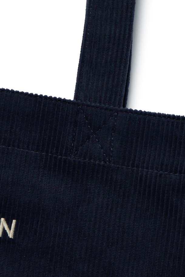 **코듀로이 에코 백 - 네이비 (P255ATO413)**

부드러운 코듀로이 소재와 면, 폴리에스테르 혼방으로 제작된 네이비 컬러의 미디엄 사이즈 에코 백입니다. 심플하고 베이직한 디자인으로 일상, 여행 등 다양한 TPO에 활용하기 좋습니다. 가방 내부에는 텀블러 포켓과 내부 포켓이 있어 실용성을 높였으며, D링을 활용하여 측면 장식을 부착할 수 있습니다. 가볍고 부드러운 촉감으로 편안하게 사용 가능하며, 자수 로고가 디자인 포인트입니다. 스타일은 캐주얼, 미니멀, 클래식 무드를 연출합니다.
