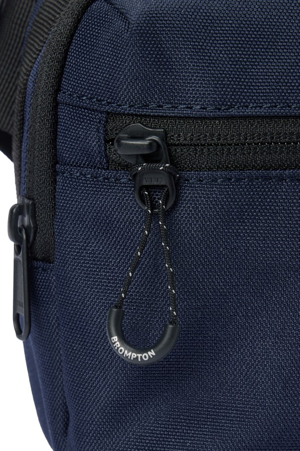 바이시클 미니백 - D/네이비 (P255ABB150)는 남성을 위한 미니 사이즈 가방입니다. 네이비 컬러의 폴리에스터와 나일론 소재로 제작되었으며, 로고 패턴과 반사 프린트 디자인이 특징입니다. 방수 기능과 패커블 디자인으로 실용성을 더했으며, 사이즈 조절이 가능합니다. 메쉬 소재 보강, 후면 지퍼, 가슴 벨트, 내부 수납 포켓, 프론트 브롬톤 로고가 돋보이며, 지퍼형 잠금 방식으로 내용물을 안전하게 보호합니다. 바이크 및 일상 용도로 사용하기 좋으며, 리플렉티브 프린트 적용으로 야간 시인성을 높였습니다.
