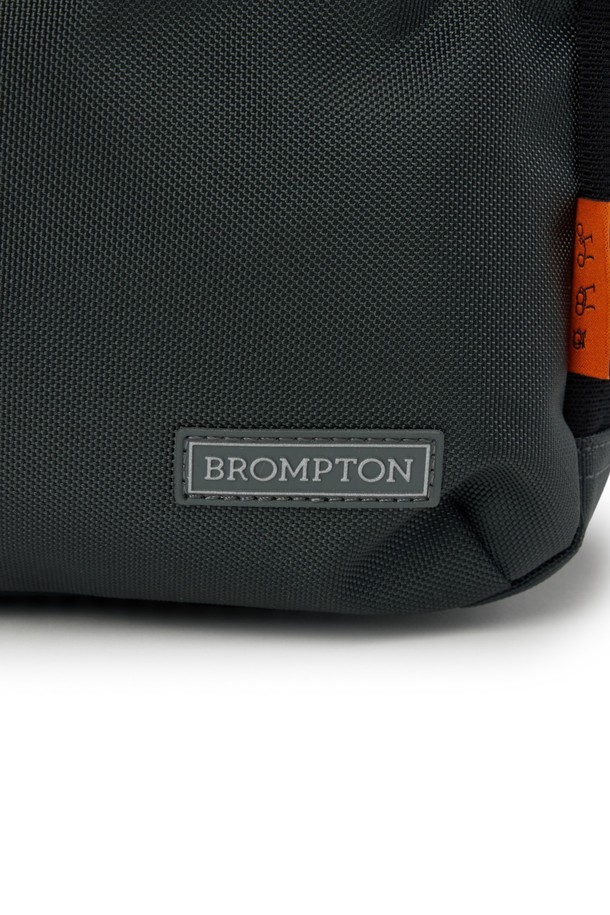 브롬톤 트래블 백 - C/그레이는 미디엄 사이즈, 무지 패턴의 남성용 가방입니다. 나일론과 폴리에스테르 소재로 제작되었으며, 사각형 모양에 브롬톤 로고 버클과 오렌지 라벨 디테일로 포인트를 주었습니다. 분리형 스트랩과 벨크로 잠금 방식, 헬멧 수납 기능이 있어 일상, 아웃도어, 통근 등 다양한 용도로 활용 가능합니다. 15.7L 용량으로 넉넉한 수납 공간을 제공하며, 미니멀, 캐주얼, 시티보이 스타일의 출근룩에 잘 어울립니다.
