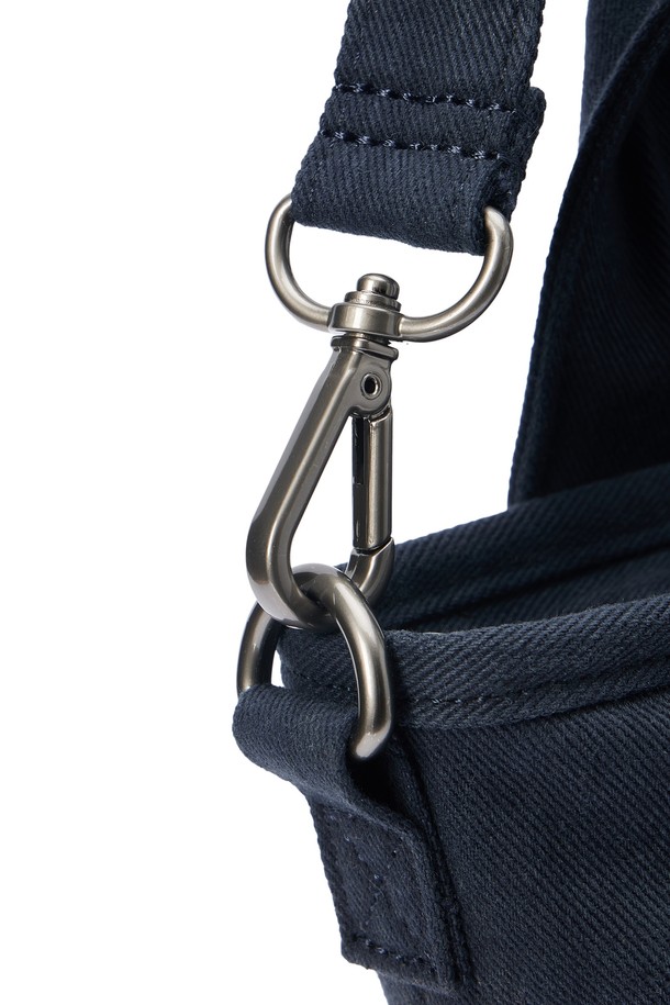 SMALL TOTE BAG (스몰 토트백) - 네이비 컬러의 남성용 토트백입니다. 면 소재로 제작되었으며, 스몰 사이즈의 사각 쉐입에 로고 패턴과 스터드/찡 및 자수 디자인 장식이 돋보입니다. 2WAY 기능과 손잡이로 다양한 연출이 가능하며, 넓은 개구부와 자연스러운 워싱 텍스처가 특징입니다. 오픈형 잠금 방식으로 편리하며, 크로스백으로도 활용 가능하여 동네 마실룩, 쇼핑룩 등 캐주얼, 미니멀, 시티보이 스타일을 연출하기 좋습니다.
