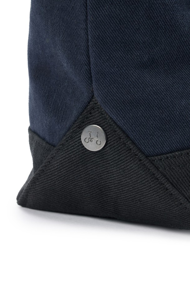 SMALL TOTE BAG (스몰 토트백) - 네이비 컬러의 남성용 토트백입니다. 면 소재로 제작되었으며, 스몰 사이즈의 사각 쉐입에 로고 패턴과 스터드/찡 및 자수 디자인 장식이 돋보입니다. 2WAY 기능과 손잡이로 다양한 연출이 가능하며, 넓은 개구부와 자연스러운 워싱 텍스처가 특징입니다. 오픈형 잠금 방식으로 편리하며, 크로스백으로도 활용 가능하여 동네 마실룩, 쇼핑룩 등 캐주얼, 미니멀, 시티보이 스타일을 연출하기 좋습니다.
